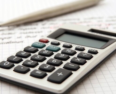 A calculator sitting on top of a spreadsheet with a pencil.