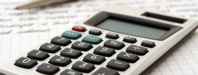 A calculator sitting on top of a spreadsheet with a pencil.